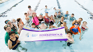 children in a pool holding a Generation H2O banner a winners of the Make a Splash Challenge