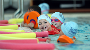 kid in swimming pool with floats