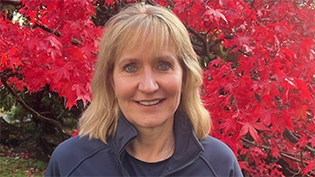 head and shoulders of Scottish Water Board Chair Deirdre Michie in front of a vibrant red leafed tree