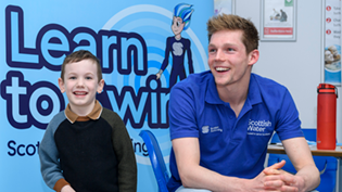 man and boy in front of Learn to Swim Signage