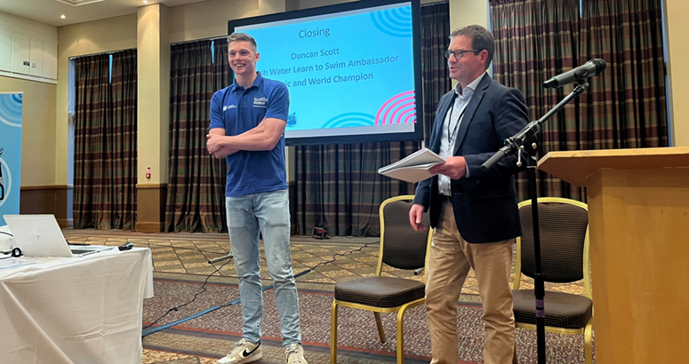Two men standing presenting in front of a screen