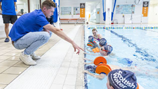 Man beside swimming pool with children in the pool