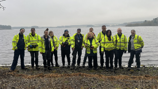 Scottish Water Rangers and Volunteers pictured together, holding tools in front of Gladhouse Reservoir